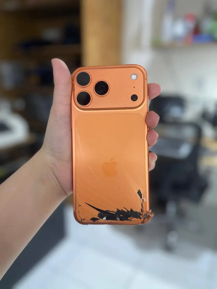 O mesmo iPhone 17 Pro Max antes, com a tampa traseira estilhaçada no canto inferior.
