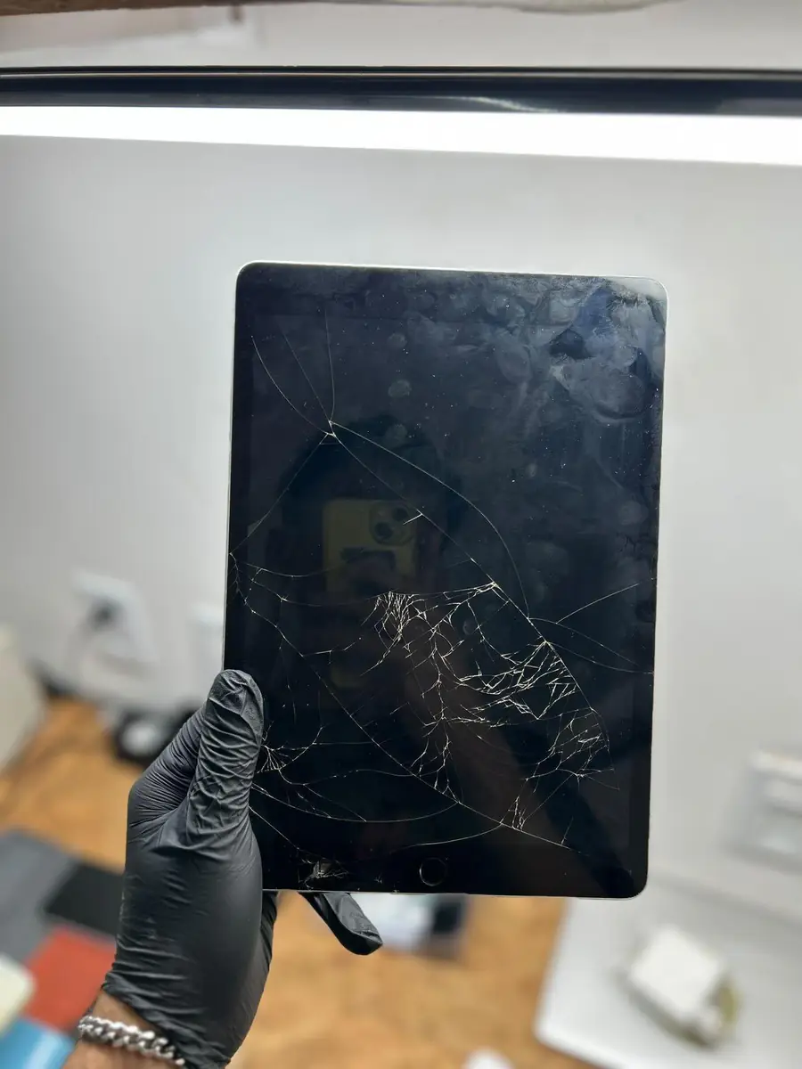 O mesmo iPad 9 antes, com o vidro da tela rachado em teia na metade inferior.